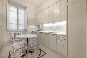 a kitchen with white cabinets and a table and a sink at Regina Elena - Antica Dimora, Bastione S. Remy in Cagliari