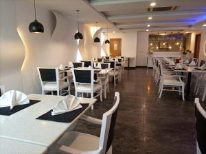 a dining room with white tables and white chairs at Falettis Express DHA in Lahore