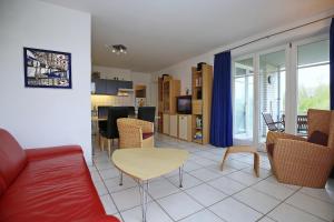 a living room with a red couch and a table at Dünenblick Wohnung 44 in Boltenhagen