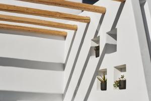 a hallway with white walls and wooden beams and potted plants at Alleys All-Suite Hotel & Spa in Pirgos