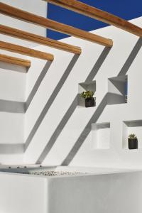 a white wall with wooden beams and potted plants at Alleys All-Suite Hotel & Spa in Pirgos