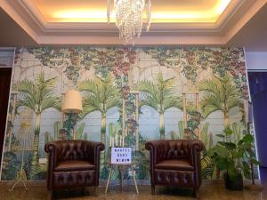 two chairs in front of a wall with a mural of palm trees at Hotel Baby in Milano Marittima +144 photos