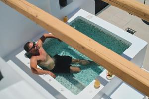 a man is sitting on the edge of a swimming pool at Alleys All-Suite Hotel & Spa in Pirgos