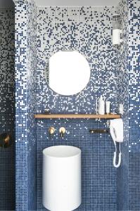 a bathroom with a white toilet in a blue tiled wall at Boutique Hotel Miramar in Monte Carlo