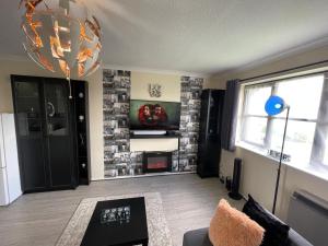 sala de estar con pared de ladrillo y lámpara de araña en WindyS Basildon Smart Home, en Basildon
