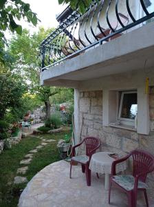 Gornji Proložac的住宿－Bungalow Angelina Imotski - Gornji Proložac，庭院里设有两张红色的椅子和一张桌子