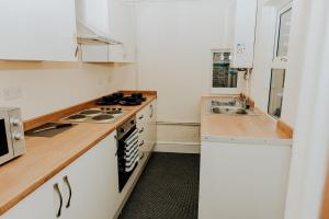 a kitchen with white cabinets and a stove and a sink at Regent park House in Etruria