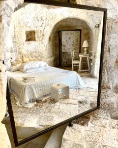 espejo en una habitación con cama y mesa en Pietrefitte, en Ostuni