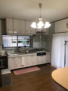 a kitchen with white cabinets and a sink and a table at Youyousanso Traditional B in Tsu