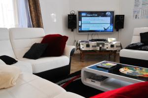 a living room with white furniture and a flat screen tv at Gite Stone Lodge in Bourcy