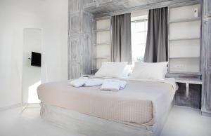 una camera bianca con un grande letto con cuscini bianchi di Crystal Dreams a Paroikia