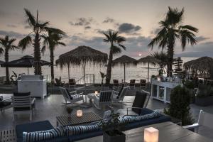 a patio with chairs and palm trees and the water at Glaros Royal Beach Hotel in Hersonissos