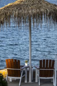 a table and two chairs under a straw umbrella at Glaros Royal Beach Hotel in Hersonissos