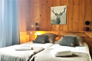 2 Betten in einem Zimmer mit einem Hirschbild an der Wand in der Unterkunft Chalet de Roselend in Beaufort