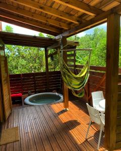 Banana Cottage Ecolodge & Spa في لو جوسيير: أرجوحة على سطح السفينة مع حوض استحمام ساخن