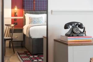 a bedroom with a bed and a phone on a table at Hotel Indigo - Cardiff, an IHG Hotel in Cardiff