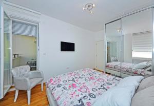 a bedroom with a bed and a chair and a mirror at Reset Apartment in Novi Sad