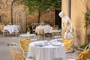 a table and chairs and a statue in a courtyard at Les Remparts Hôtels et Demeures Historiques in Beaune