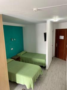 two beds in a room with green walls at Koka Beach in Playa del Ingles