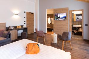 a bedroom with a bed and chairs and a tv at Àlia Bianca Active & Family Hotel in Andalo