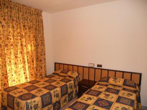 a bedroom with two beds and a curtain at Apartamentos Indasol in Salou