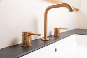 a kitchen sink with two copper faucets on it at Plaza Apartments in Opatija +37 photos
