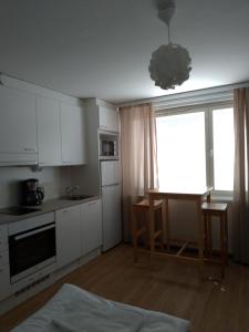 cocina con armarios blancos, mesa y ventana en Apartments Käyräkatu, en Jyväskylä