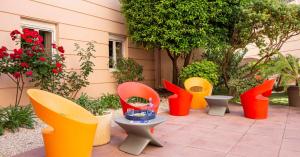 a group of different colored chairs sitting next to a building at Hotel Port Marine in Sète