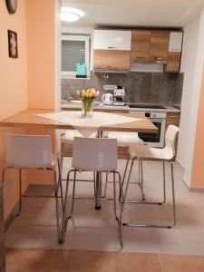 uma cozinha com uma mesa de madeira e cadeiras em Veronica nyaralóház em Zamárdi