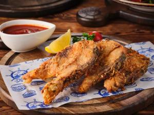 two pieces of fish on a plate with a bowl of dipping sauce at Лайнер Горный Курортный Комплекс Layner в Чимгане in Chimgan