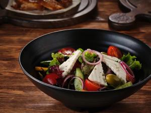 un tazón negro lleno de verduras en una mesa de madera en Лайнер Горный Курортный Комплекс Layner в Чимгане, en Chimgan