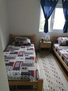 two twin beds in a room with blue curtains at Stari dud Beserovina in Bajina Bašta