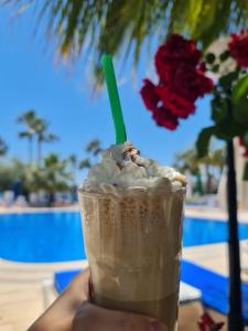 a hand holding a milkshake with a green straw at Nagi Beach Hotel in Gümbet