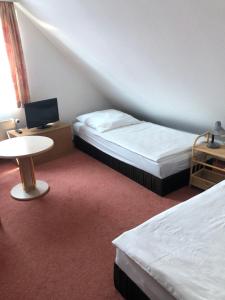 a room with two beds and a table and a tv at Ferienwohnung am Borgwallsee in Steinhagen