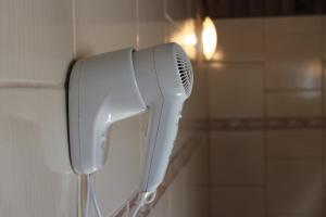 un secador de pelo blanco colgado en la pared en Motel Cisne Blumenau (Adult Only), en Blumenau
