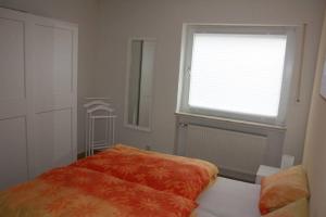 1 dormitorio con cama de color naranja y ventana en Ferienwohnung Solmsbachtalblick, en Braunfels