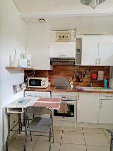 una cucina con armadi bianchi e un tavolo con una sedia di La girolle a Hourtin Altre 6 foto