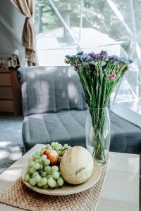 a plate of food on a table with a vase of flowers at Глэмпинг СФЕРА in Krasnaya Polyana