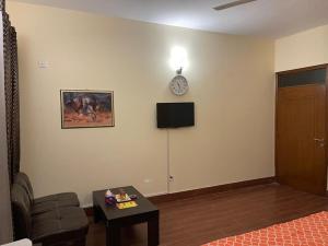 Hotel Executive Lodge في كراتشي: غرفة معيشة مع أريكة وساعة على الحائط
