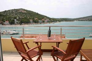 una mesa con una botella de vino y copas en el balcón en Villa Stegic, en Tisno