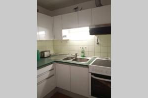 a kitchen with white cabinets and a sink at Seewohnung Ossiachersee atemberaubendes Panorama in Villach