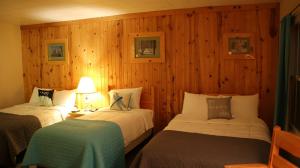 two beds in a room with wooden walls at Holiday Motel in Manistique