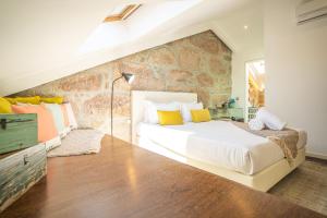 1 dormitorio con 1 cama grande y pared de piedra en CHARM by YoursPorto en Vila Nova de Gaia