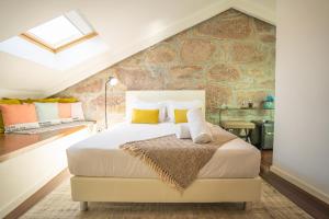 a bedroom with a king sized bed with a stone wall at CHARM by YoursPorto in Vila Nova de Gaia +13 photos