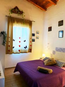 - une chambre avec un lit violet et une fenêtre dans l'établissement Villa Viola, à Agnone Bagni