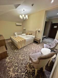 a bedroom with a bed and a couch and chairs at J'adore Boutique Hotel in Lugoj