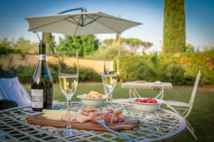 a table with two glasses of wine and a plate of food at Villa Ape Rosa Relais in Florence