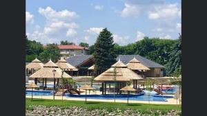 a resort with a pool with chairs and umbrellas at Bezsó apartman in Hajdúszoboszló