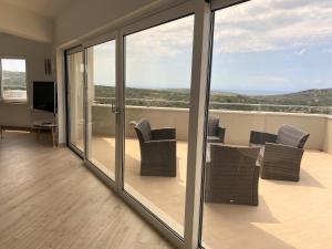 a living room with glass doors and chairs on a balcony at Apartments Carpe Diem in Primo&scaron;ten