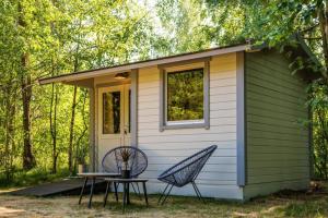 a tiny house with a table and two chairs at A Tiny House Near The Beach in Pērkone